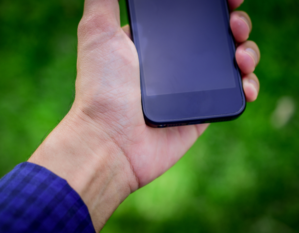 smartfon na tle zieleni w dłoni męskiej